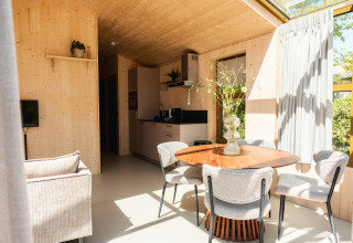 Interno luminoso e moderno di una lodge con tavolo in legno e grandi finestre nei Paesi Bassi.