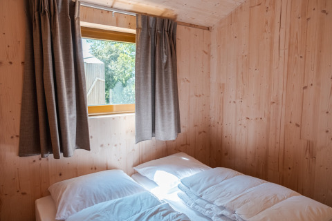 Camera luminosa in legno con letto matrimoniale e finestra in «Large Green House 4 persons» nei Paesi Bassi.