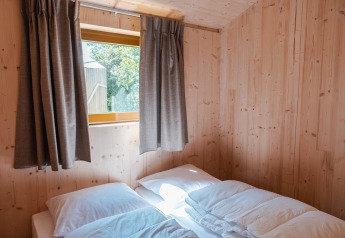 Lichte houten slaapkamer met dubbel bed en raam in ‘Large Green House 4 persons’ in Nederland.