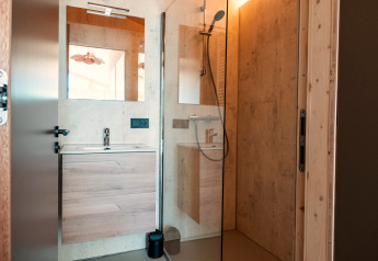 Moderne badeværelse med glasbruser, trævægge, vask og spejl i Large Green House for 4 personer.