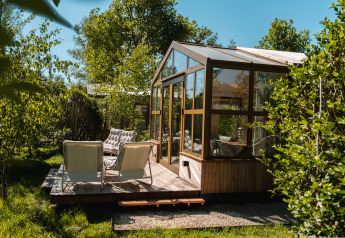 Houten terras en serre bij het Large Green House voor 4 personen, omgeven door groen in Nederland.
