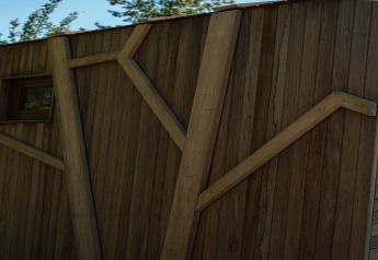 Houten gevel van 'Large Green House 4 persons' lodge in Nederland met takvormige versieringen.