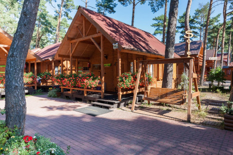 Bungalow in legno con tetti rossi e fiori a Domki letniskowe Pobierowo immersi tra gli alberi.