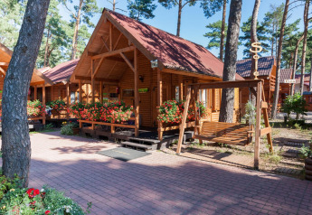 Bungalow in legno con tetti rossi e fiori a Domki letniskowe Pobierowo immersi tra gli alberi.
