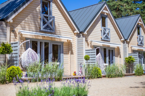 Bright holiday cottage for 5 in Pobierowo, featuring hanging chairs, garden, and a warm, modern facade.