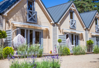 Bright holiday cottage for 5 in Pobierowo, featuring hanging chairs, garden, and a warm, modern facade.