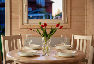 Ronde eettafel gedekt voor vier met tulpen in vaas, gefotografeerd in Aquarius Cottages, Duitsland.