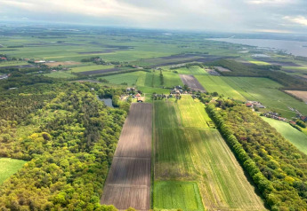 Vista aerea di un lodge circondato da campi verdi, foreste e terreni agricoli sotto un cielo nuvoloso.