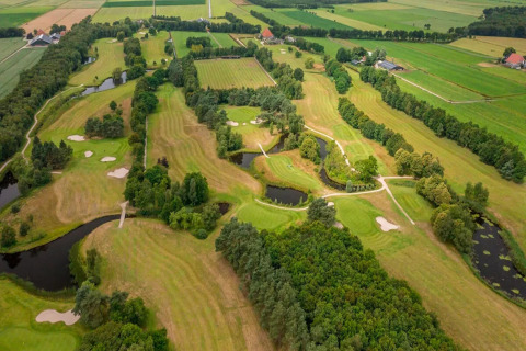 Vista aerea di un lodge con campo da golf, circondato da alberi, laghetti e distese di prati verdi.
