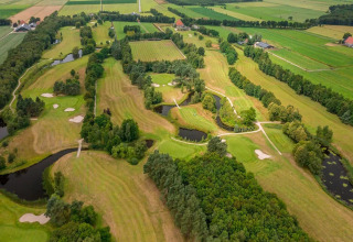 Vista aerea di un lodge con campo da golf, circondato da alberi, laghetti e distese di prati verdi.