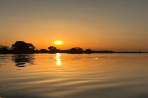 Tramonto su un lago alla lodge Op'e Pleats 1 nei Paesi Bassi, acqua calma che riflette il cielo arancione.
