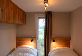 Due letti singoli in una stanza accogliente della lodge Op'e Pleats 1 nei Paesi Bassi, con mobili in legno.