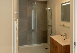 Bagno moderno nella lodge Op'e Pleats 1 nei Paesi Bassi con doccia, lavandino e specchio.