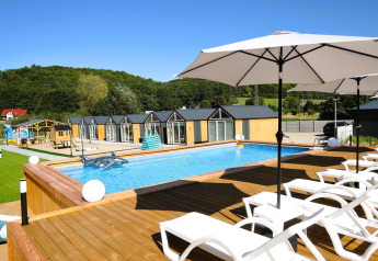 Outdoor swimming pool with sun loungers and umbrellas in front of cabins at Turkusowa osada Wapnica.