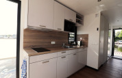 Cuisine moderne sur une péniche aux Pays-Bas avec armoires blanches et plan de travail en bois.