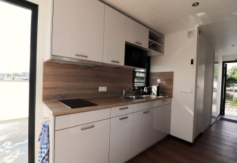 Cuisine moderne sur une péniche aux Pays-Bas avec armoires blanches et plan de travail en bois.