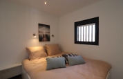 Chambre avec lit double, coussins, fenêtre à barreaux et tableau sur Houseboat « Refugio » aux Pays-Bas.