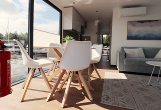 Salon et salle à manger modernes sur le Houseboat Refugio aux Pays-Bas, avec grandes fenêtres et vue sur l’eau.