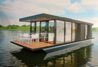 Moderne Houseboat Refugio ses på vandet, omgivet af grøn natur og blå himmel, med en åben terrasse.