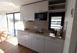 Moderne køkkenindretning ombord på husbåden «Refugio» i Nederlandene med store vinduer og spiseplads.