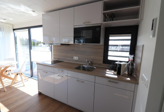 Moderne køkkenindretning ombord på husbåden «Refugio» i Nederlandene med store vinduer og spiseplads.