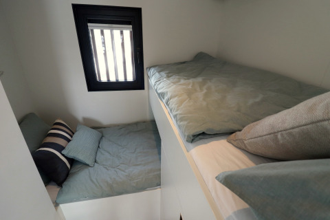 Deux petits lits avec couvre-lits verts dans la Houseboat «Refugio» aux Pays-Bas, près d’une fenêtre.
