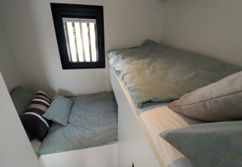 To små senge med grønne dyner på Houseboat «Refugio» i Holland, tæt vindue med mørk ramme.