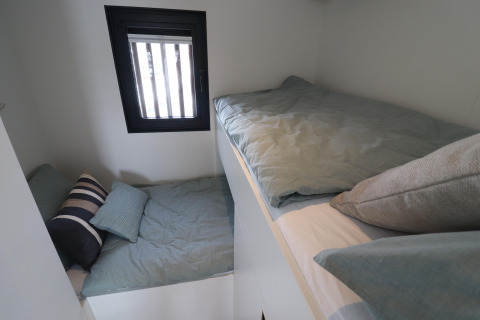 Dos pequeñas camas con sábanas verdes en la Houseboat «Refugio» en Países Bajos, junto a la ventana.