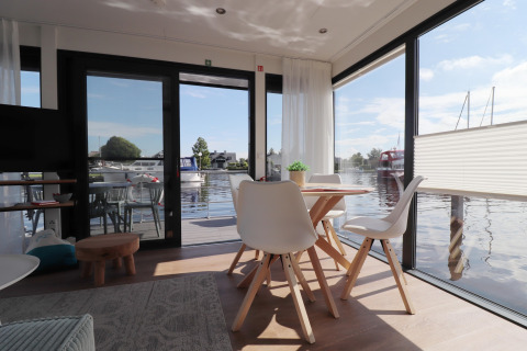 Interieur van houseboat 'Refugio' in Nederland met moderne eethoek en zicht op het water.