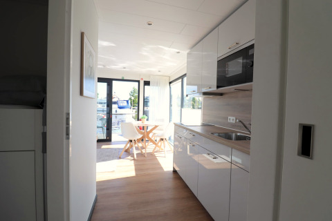 Moderne køkken og spiseplads om bord på husbåden Refugio i Holland med udsigt over vandet.