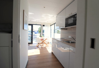Modern kitchen and dining area on Houseboat Refugio in the Netherlands with large windows overlooking water.