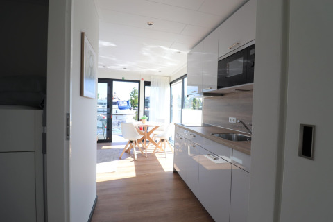 Moderne Küche und Essbereich auf dem Hausboot Refugio in den Niederlanden mit Blick auf das Wasser.