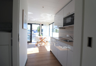 Moderne køkken og spiseplads om bord på husbåden Refugio i Holland med udsigt over vandet.