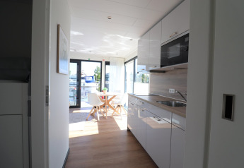 Cucina moderna e zona pranzo a bordo dell’houseboat Refugio nei Paesi Bassi con vista sull’acqua.