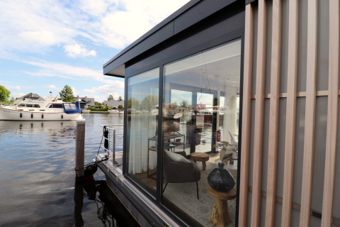 Udsigt til Houseboat «Refugio» i Holland med glasvægge, moderne indretning og både på vandet.