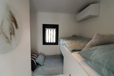 Moderne soveværelse med køjesenge og minimalistisk indretning på husbåd Refugio i Holland.