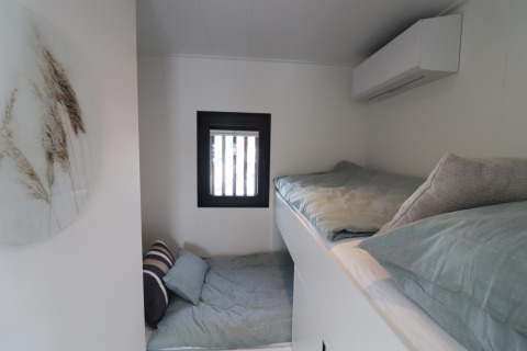 Moderne soveværelse med køjesenge og minimalistisk indretning på husbåd Refugio i Holland.