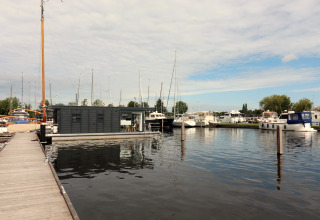 Moderne Hausboot Refugio am Steg mit mehreren Yachten und Segelbooten bei bewölktem Himmel in Holland