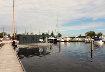 Moderne husbåd ved havn med flere sejlbåde og motorbåde, Houseboat Refugio, Holland, overskyet dag