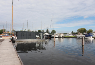 Houseboat Refugio moderno ormeggiato al molo tra barche a vela e motoscafi in una giornata nuvolosa in Olanda