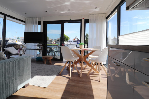Helles Wohnzimmer im Hausboot 'Refugio' in den Niederlanden mit Essbereich, Sofa und Blick aufs Wasser.