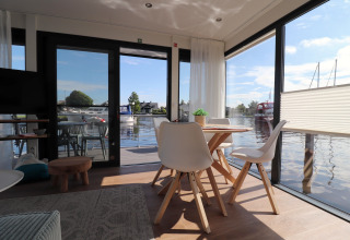 Intérieur moderne et lumineux du houseboat Refugio avec grandes fenêtres sur l’eau aux Pays-Bas.