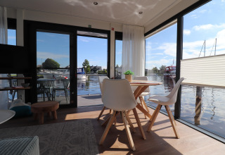 Interni luminosi e moderni della houseboat Refugio con grandi finestre e vista sull'acqua nei Paesi Bassi.