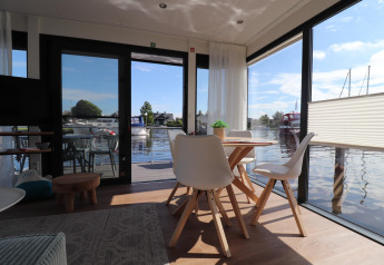 Interni luminosi e moderni della houseboat Refugio con grandi finestre e vista sull'acqua nei Paesi Bassi.