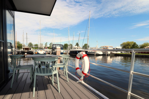 Udsigt fra Houseboat Refugio i Holland, med udendørs siddeplads, redningskrans og både i havnen.