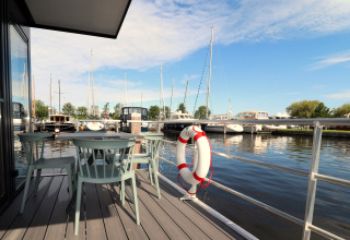 Udsigt fra Houseboat Refugio i Holland, med udendørs siddeplads, redningskrans og både i havnen.
