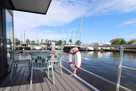 Udsigt fra Houseboat Refugio i Holland, med udendørs siddeplads, redningskrans og både i havnen.