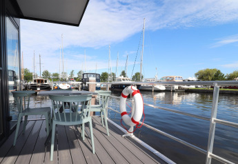 Vue depuis Houseboat Refugio aux Pays-Bas, assises extérieures, bouée de sauvetage et port avec bateaux.