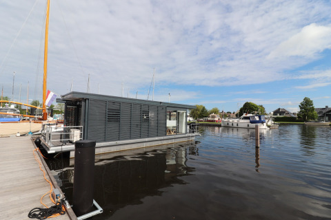 Houseboat moderno Refugio ormeggiato in un porto turistico nei Paesi Bassi, circondato da barche e acqua.