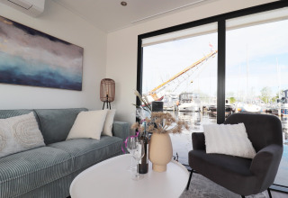 Wohnzimmer auf Hausboot 'Refugio' in den Niederlanden mit moderner Einrichtung und Blick auf den Jachthafen.
